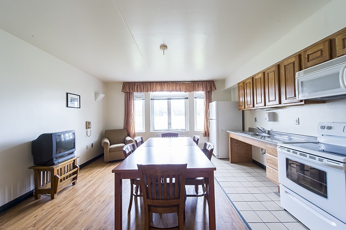 West Wing Community Kitchen - large dining table with chairs a tv and kitchen